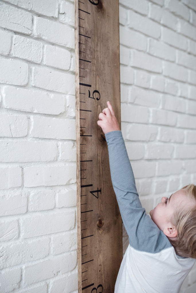 little-boy-measuring-how-tall-with-white-loft-growth-chart