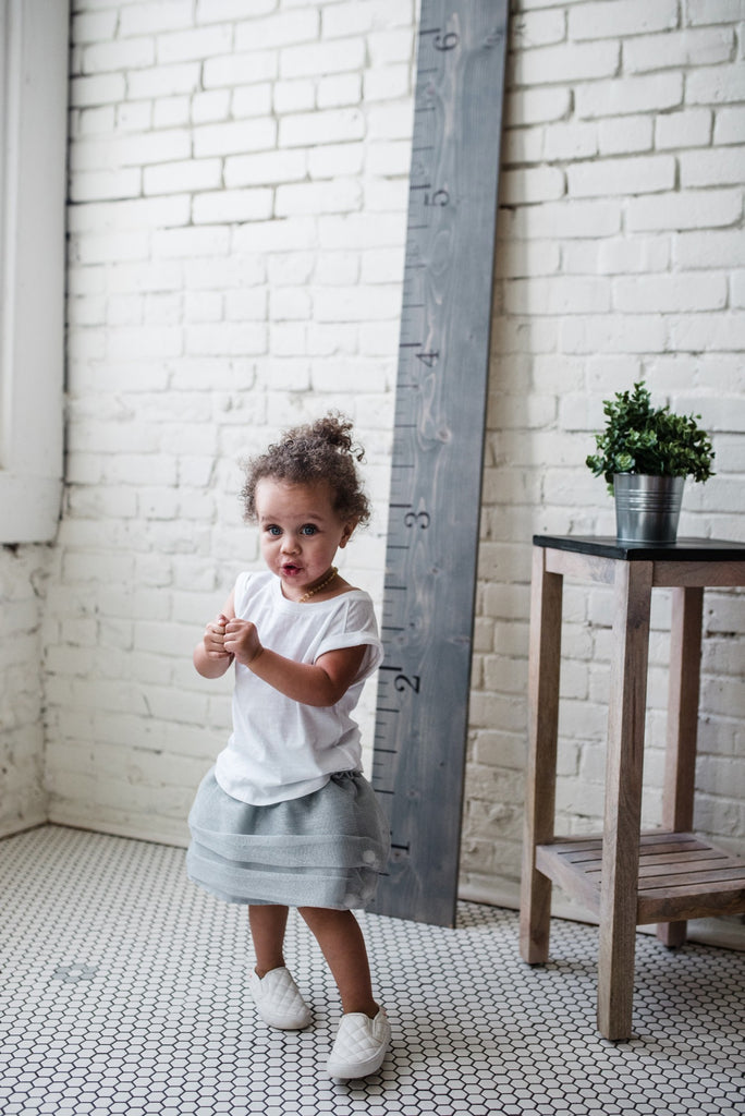 little-girl-in-skirt-and-white-shoes-dancing-in-pretty-white-gray-farmhouse-girls-room